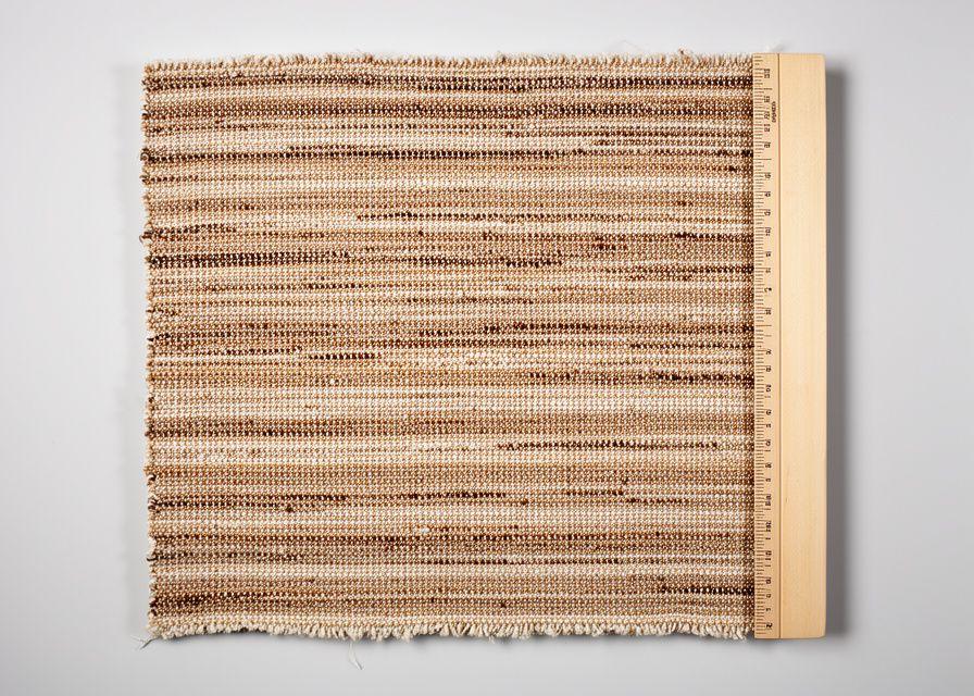 Handwoven textile sample laid flat beside a ruler and softbox reflection in a teaching studio